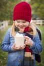 Smiling Young Girl Holding Cocoa Mug with Marsh Mallows Outside