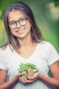 Smiling young girl holding in her hand fresh peas