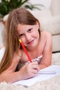 Smiling young girl lying and writing in notebook Royalty Free Stock Photo