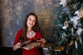 Smiling young girl in red dress with presents and gift boxes under the Christmas tree Royalty Free Stock Photo