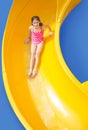 Smiling Young girl riding down a yellow water slide Royalty Free Stock Photo