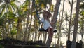 Smiling young girl rolling on a swing in tropical forest