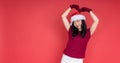 Smiling young girl with santa hat showing heart with two hands, love sign. Isolated over red background. Concept of the New Year Royalty Free Stock Photo