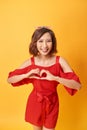 Smiling young girl showing heart with two hands, love sign. Isolated over yellow background Royalty Free Stock Photo