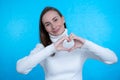 Smiling young girl showing heart with two hands, love sign.  over blue background Royalty Free Stock Photo