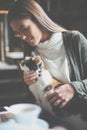 Smiling young girl sitting in cafe and holding her pet cat. Royalty Free Stock Photo