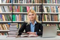 Smiling young girl sitting at a desk in the library working with Royalty Free Stock Photo