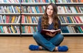 Smiling young girl sitting on the floor in the library with cros Royalty Free Stock Photo