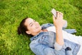 Smiling young girl with smartphone lying on grass