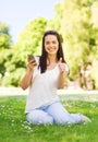 Smiling young girl with smartphone sitting in park Royalty Free Stock Photo