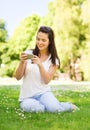 Smiling young girl with smartphone sitting in park Royalty Free Stock Photo