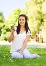 Smiling young girl with smartphone sitting in park Royalty Free Stock Photo