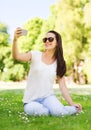 Smiling young girl with smartphone sitting in park Royalty Free Stock Photo