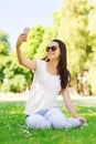 Smiling young girl with smartphone sitting in park Royalty Free Stock Photo