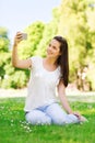 Smiling young girl with smartphone sitting in park Royalty Free Stock Photo