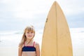 Smiling young girl standing next to surfboard Royalty Free Stock Photo