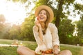 Smiling young girl in summer hat having a picnic at the park, sitting on a grass Royalty Free Stock Photo