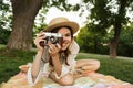 Smiling young girl in summer hat having a picnic at the park, sitting on a grass, Royalty Free Stock Photo