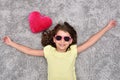 Young girl with sunglasses and red plush heart lying on the carpet Royalty Free Stock Photo