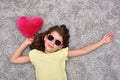 Young girl with sunglasses and red plush heart lying on the carpet Royalty Free Stock Photo