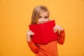 Smiling young girl in sweater hiding behind the book Royalty Free Stock Photo