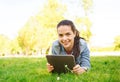 Smiling young girl tablet pc lying on grass Royalty Free Stock Photo