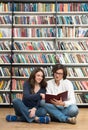 Smiling young girl and young man sitting on the floor in the lib