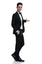 Smiling young groom in tuxedo presenting to side Royalty Free Stock Photo