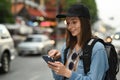 Smiling young hipster female traveler searching direction on smart phone. Life, people, travel and technology concept Royalty Free Stock Photo