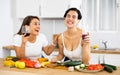 Smiling Hispanic women drinking wine and cooking in home kitchen Royalty Free Stock Photo