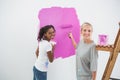 Smiling young housemates painting wall pink Royalty Free Stock Photo