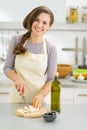 Smiling young housewife cutting fresh cheese