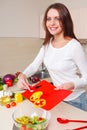 Smiling young housewife mixing fresh salad