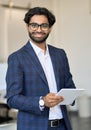 Smiling young indian business man wearing suit holding tablet, vertical. Royalty Free Stock Photo