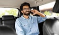 Smiling young indian man talking over phone, sitting in taxi Royalty Free Stock Photo