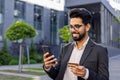 Smiling young Indian man using smartphone and holding credit card outdoors Royalty Free Stock Photo