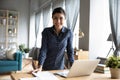 Smiling young indian woman freelancer standing at table with computer. Royalty Free Stock Photo