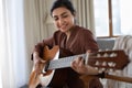 Smiling young indian woman playing guitar at home. Royalty Free Stock Photo