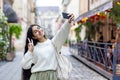 Smiling young Indian woman traveling and walking on city street, standing and taking selfie on mobile phone, showing Royalty Free Stock Photo
