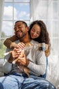 Smiling young interracial couple with coffee playing with chihuahua dog in sunlight at home in morning Royalty Free Stock Photo