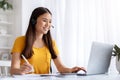 Smiling young korean woman using headset while working at home office desk Royalty Free Stock Photo