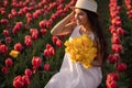 Smiling young lady with bunch of tulips sitting in field at sunset Royalty Free Stock Photo