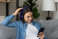 Female teenager in headset play mobile game satisfied with sound