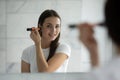 Smiling young lady standing at mirror applying flour on cheekbones Royalty Free Stock Photo