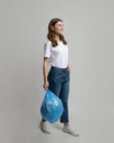 Smiling Young Lady Walking With Garbage Bag In Hands Over Gray Background Royalty Free Stock Photo