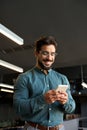 Smiling young Latin business man using cellphone at work in office. Vertical Royalty Free Stock Photo