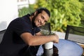 Smiling young latino man embracing a pot whit plants