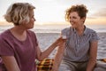 Smiling lesbian couple sitting on a beach blanket at sunset Royalty Free Stock Photo
