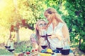 Smiling young lesbian couple women sitting affectionately together outdoors drinking red wine while bonding