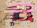 Smiling young lovers sunbathing at sandy beach Royalty Free Stock Photo